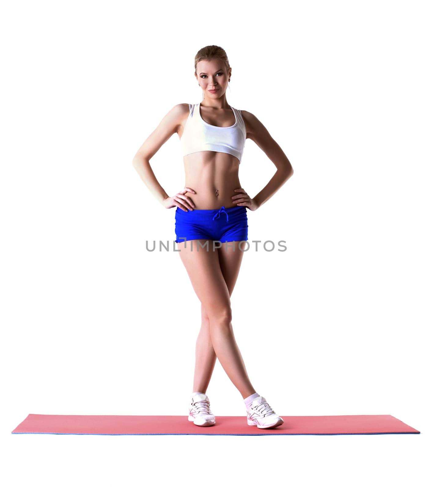 Beautiful slim woman posing on gymnastic mat in studio
