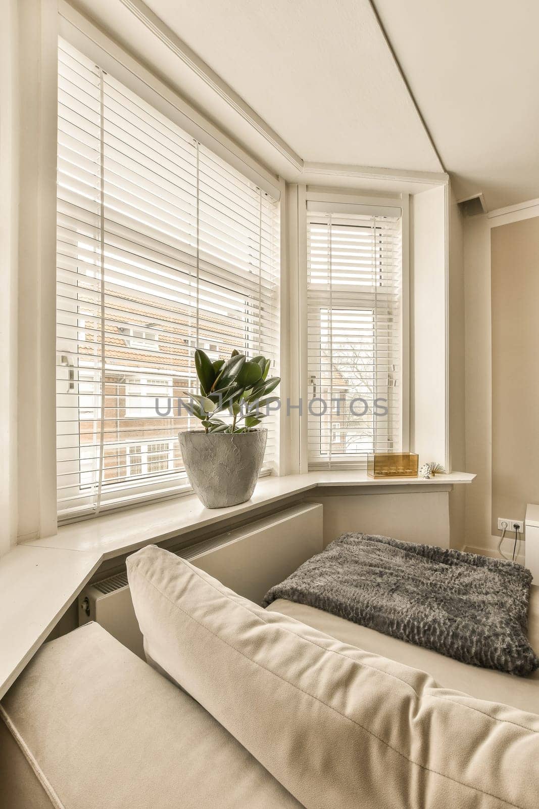 a bed in a room with blinds on the window and a plant in a vase sitting on top of it
