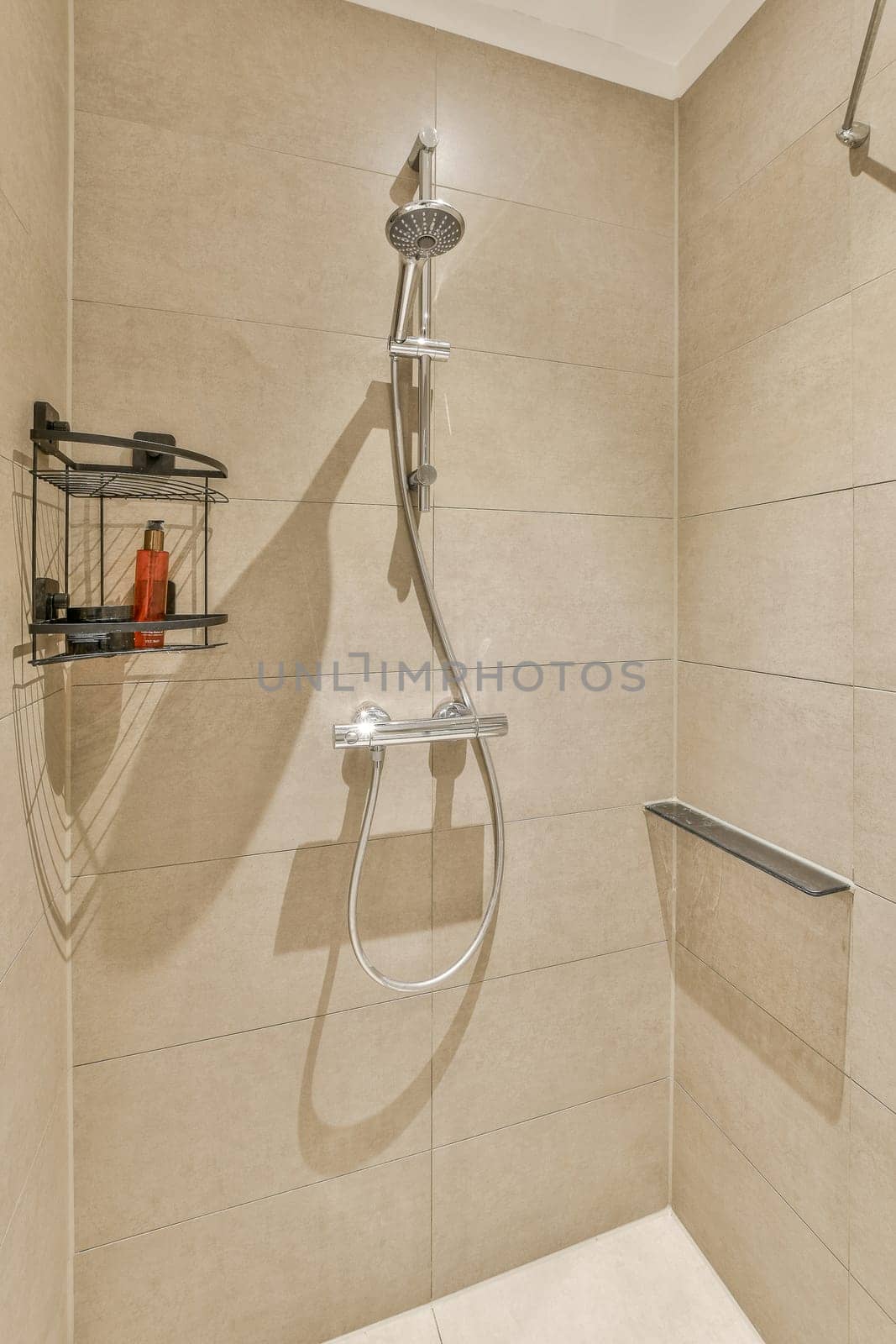 a shower stall in a bathroom with tile walls and white tiles on the wall behind it is a towel rack