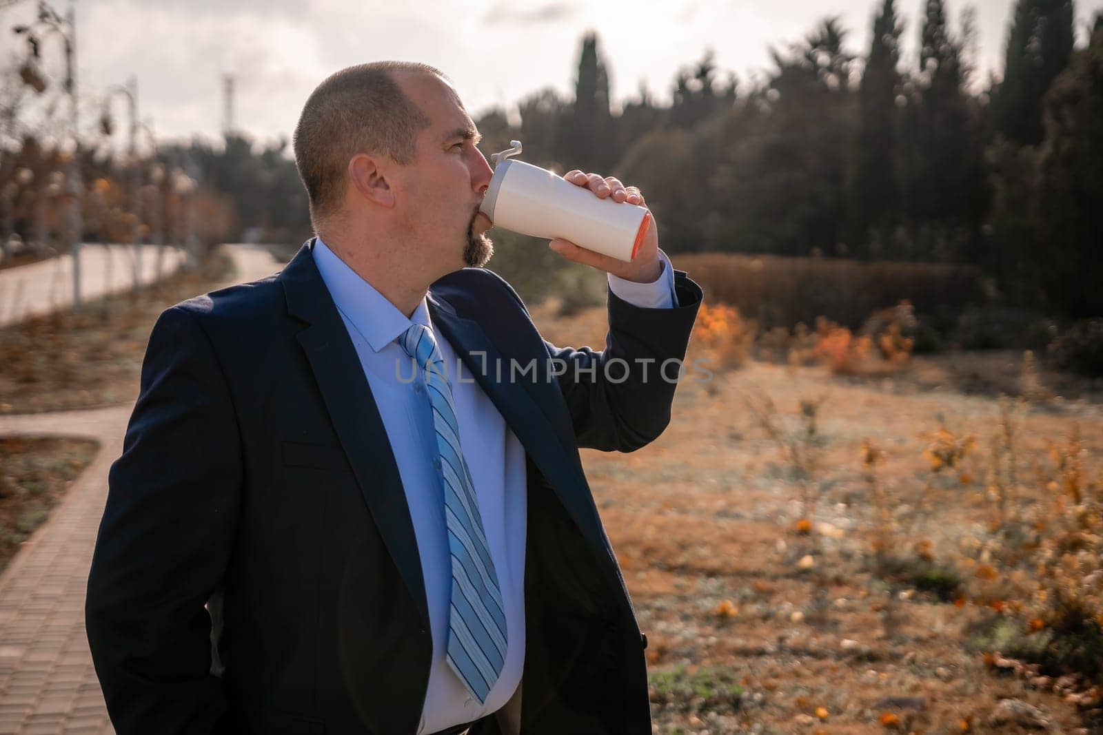 Mature entrepreneur drink coffee in autumn park. Senior executive rest in city park.