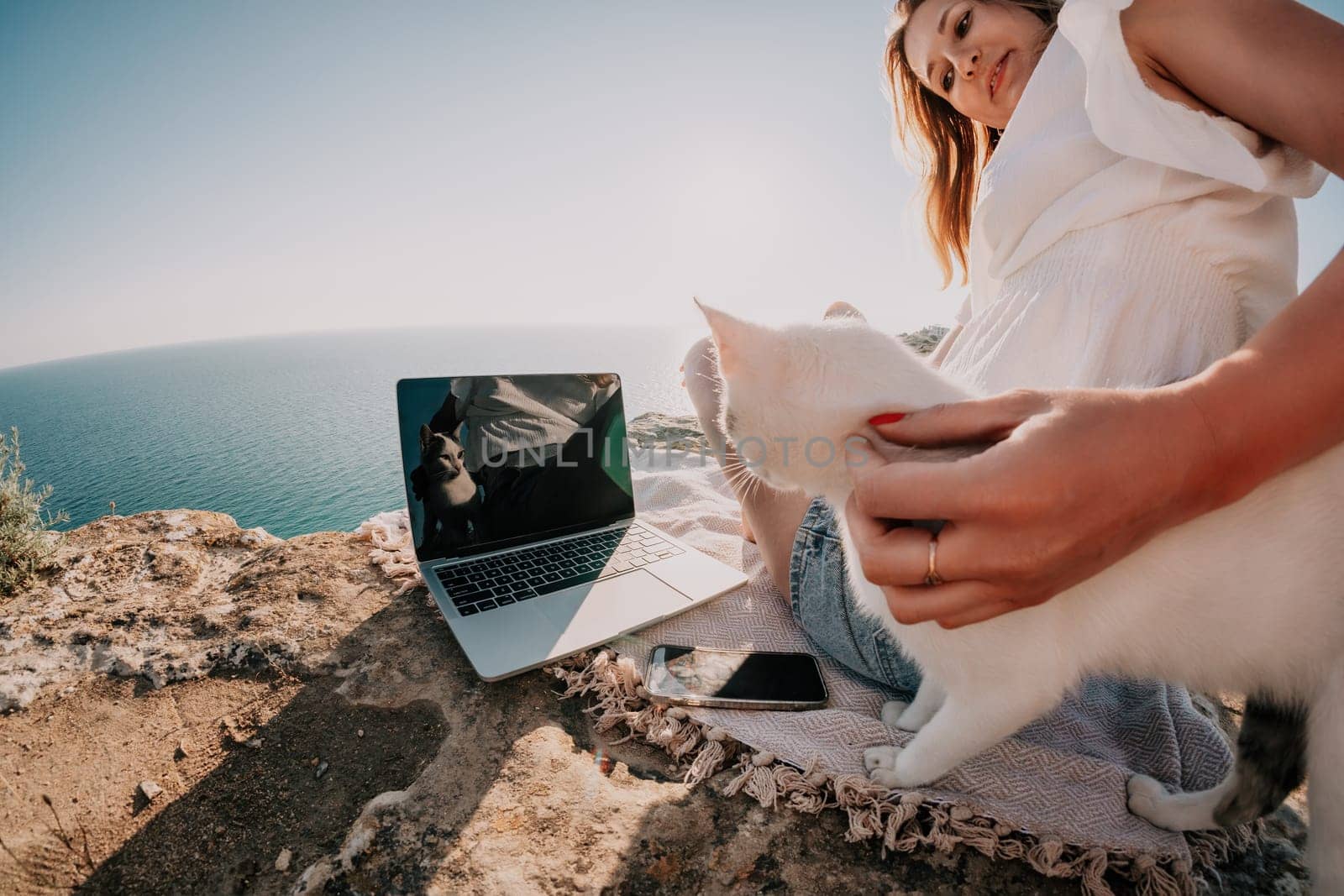 Woman sea laptop. Business woman petting cat and working on laptop by the sea. Close up on hands of pretty lady typing on computer outdoors summer day. Freelance, digital nomad and holidays concept. by panophotograph