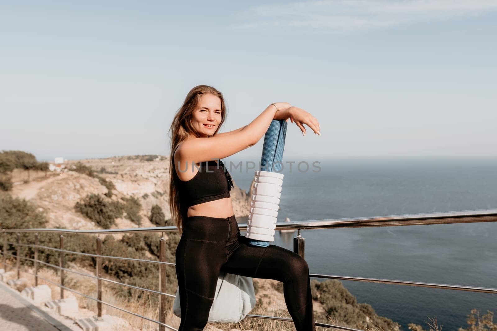 Fitness woman sea. Outdoor workout on yoga mat in park near to ocean beach. Female fitness pilates yoga routine concept. Healthy lifestyle. Happy fit woman exercising with rubber band in park.