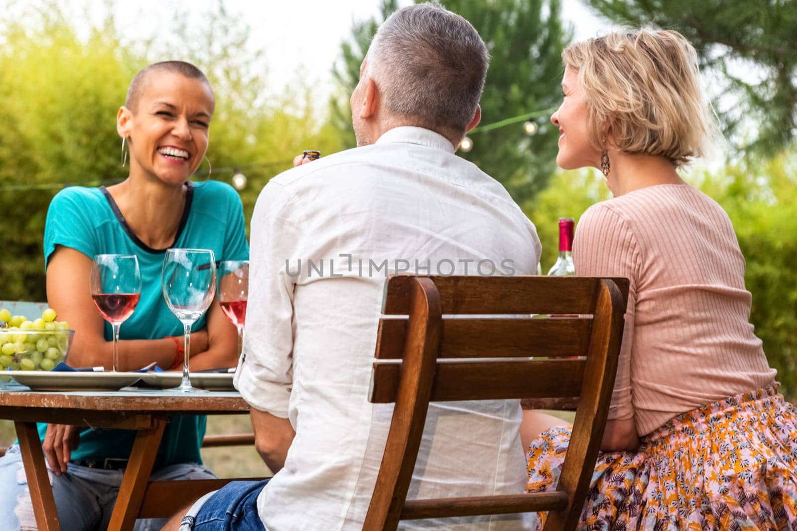 Happy and smiling woman talking to friends during garden dinner party. Lifestyle and leisure time concept.