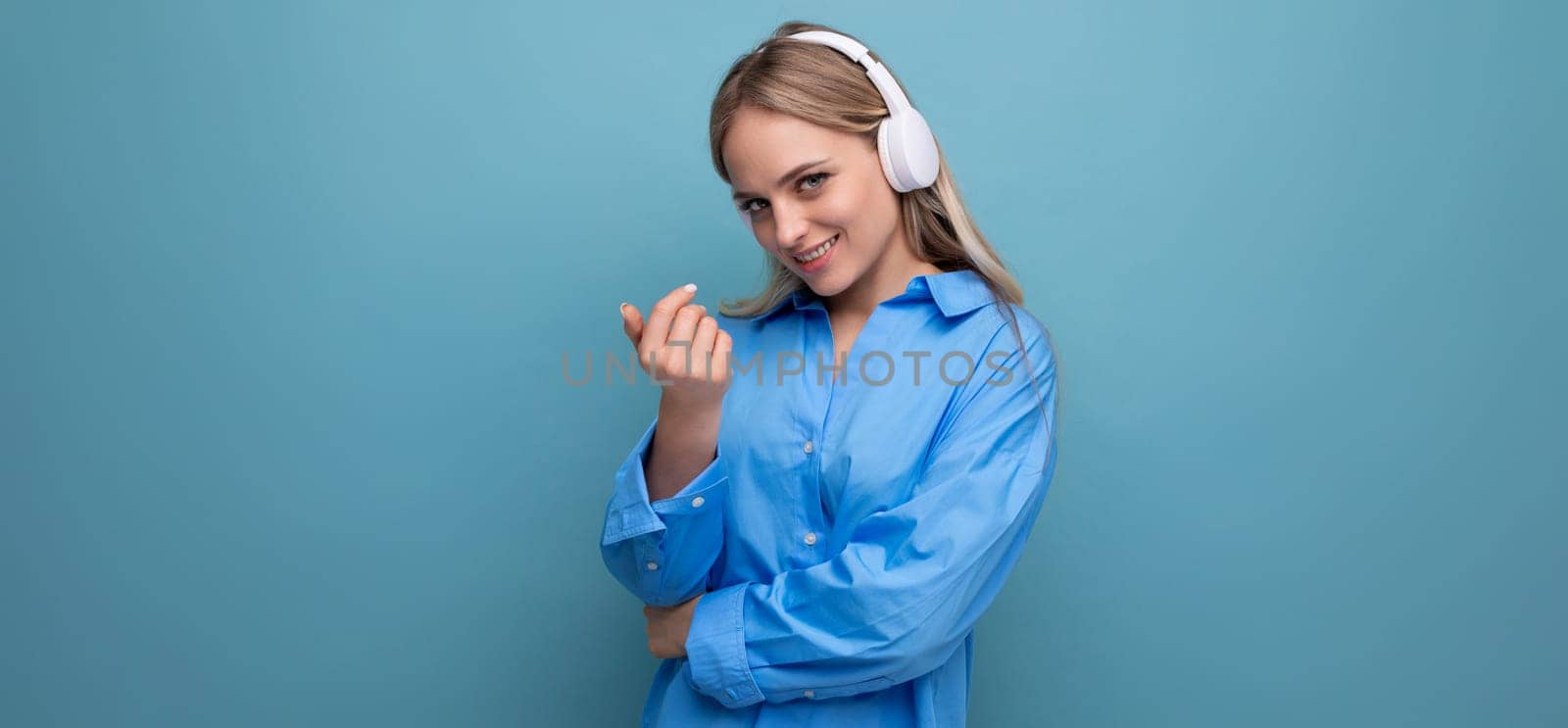a girl in wireless large headphones enjoys and relaxes to the music from the application on a blue background by TRMK