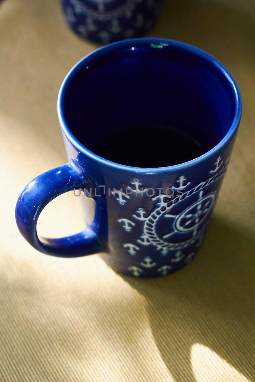 Blue ceramic cup with handwheels pattern on the table. Tea drinking. Lunch. Sea-themed dishes.