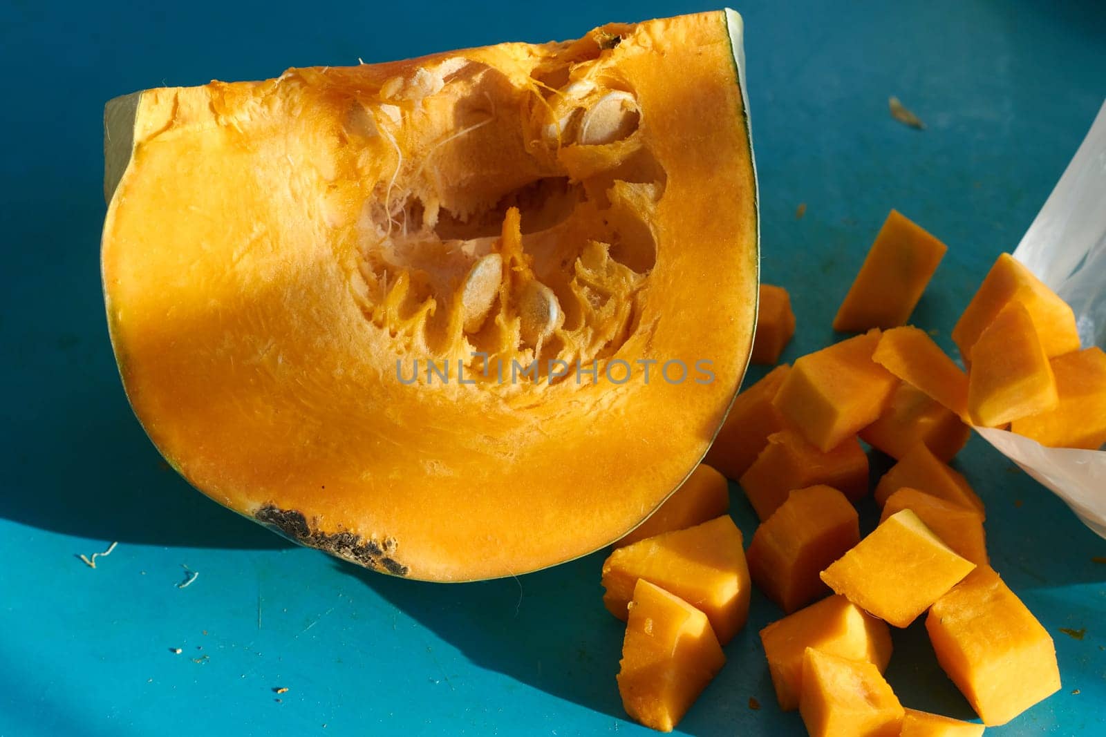 A piece of ripe orange pumpkin and sliced pumpkin on a blue background. Harvest from the garden. Storage of vegetables in winter.