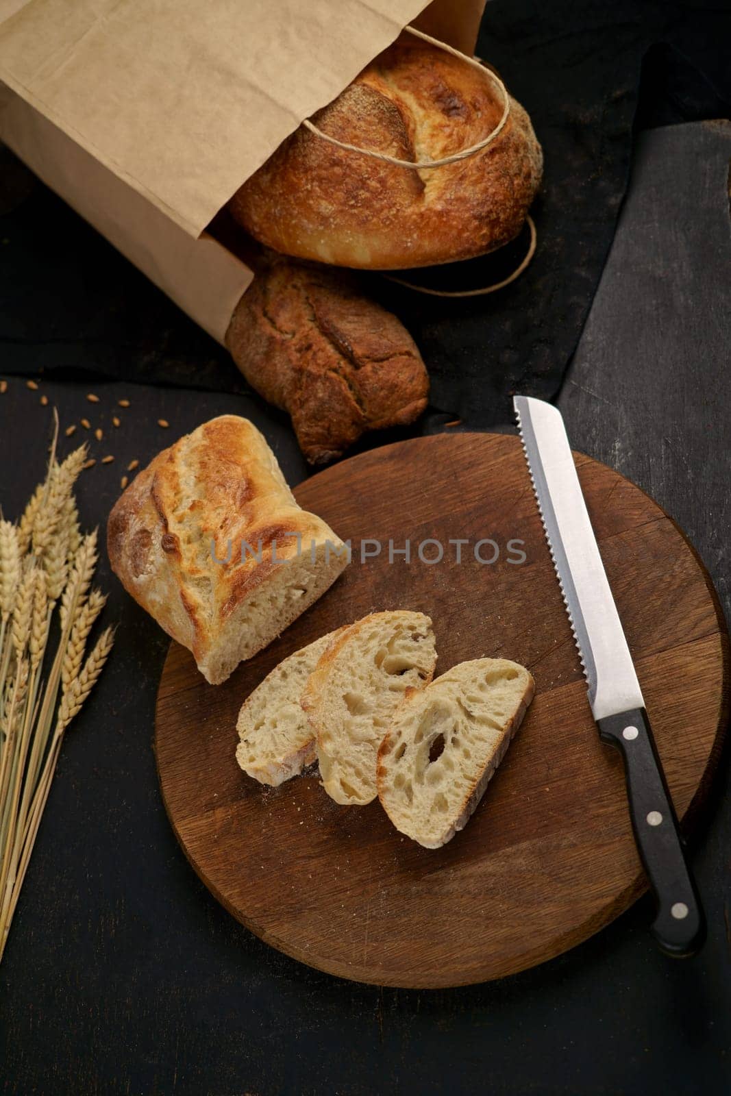 Freshly baked rye bread on a wooden board. Whole grain bread put on kitchen wood plate with a knife for cut. Fresh bread on table close-up. Fresh bread on the kitchen table