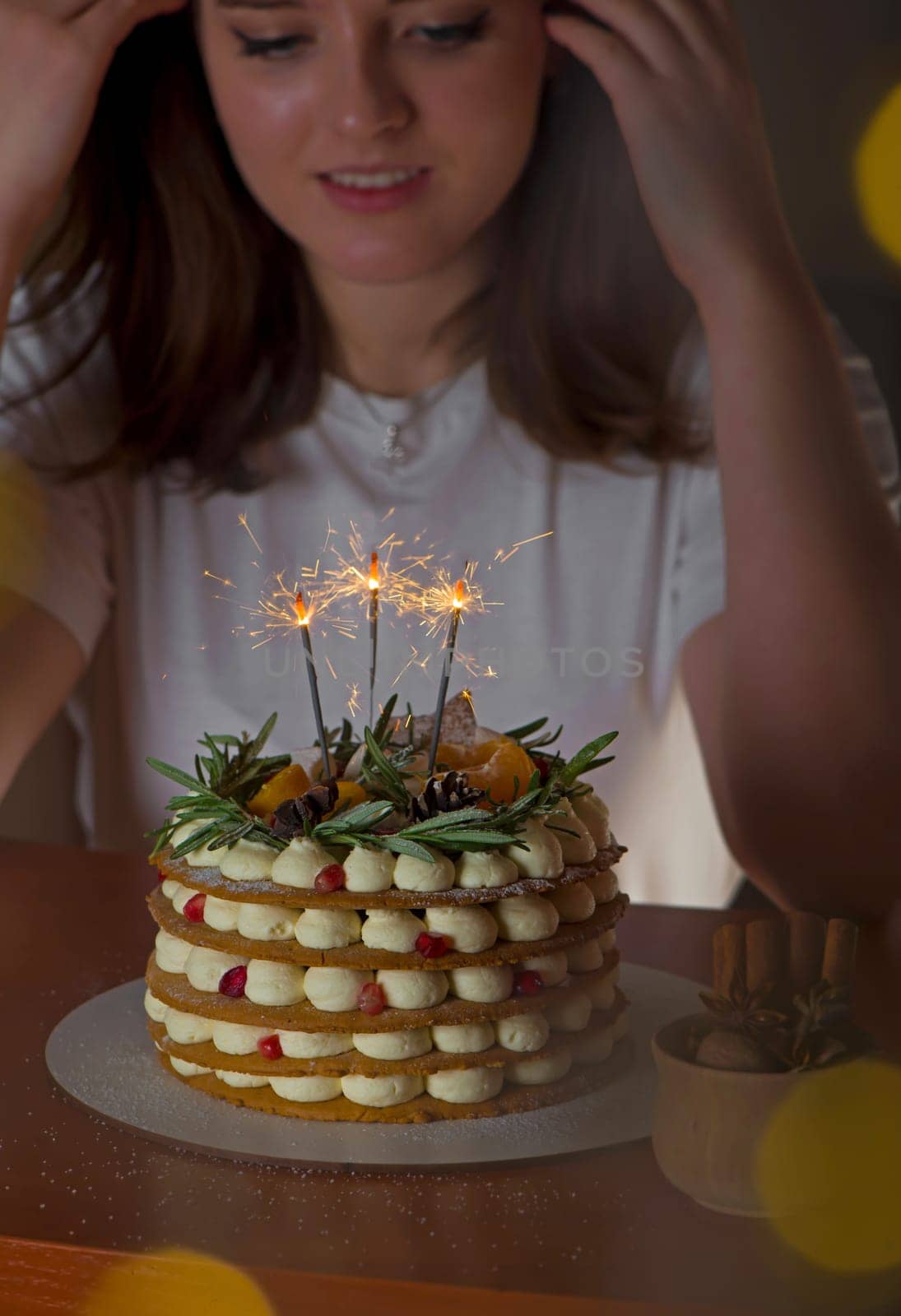 Young blonde girl in her kitchen holding a Christmas cake enjoying the smell