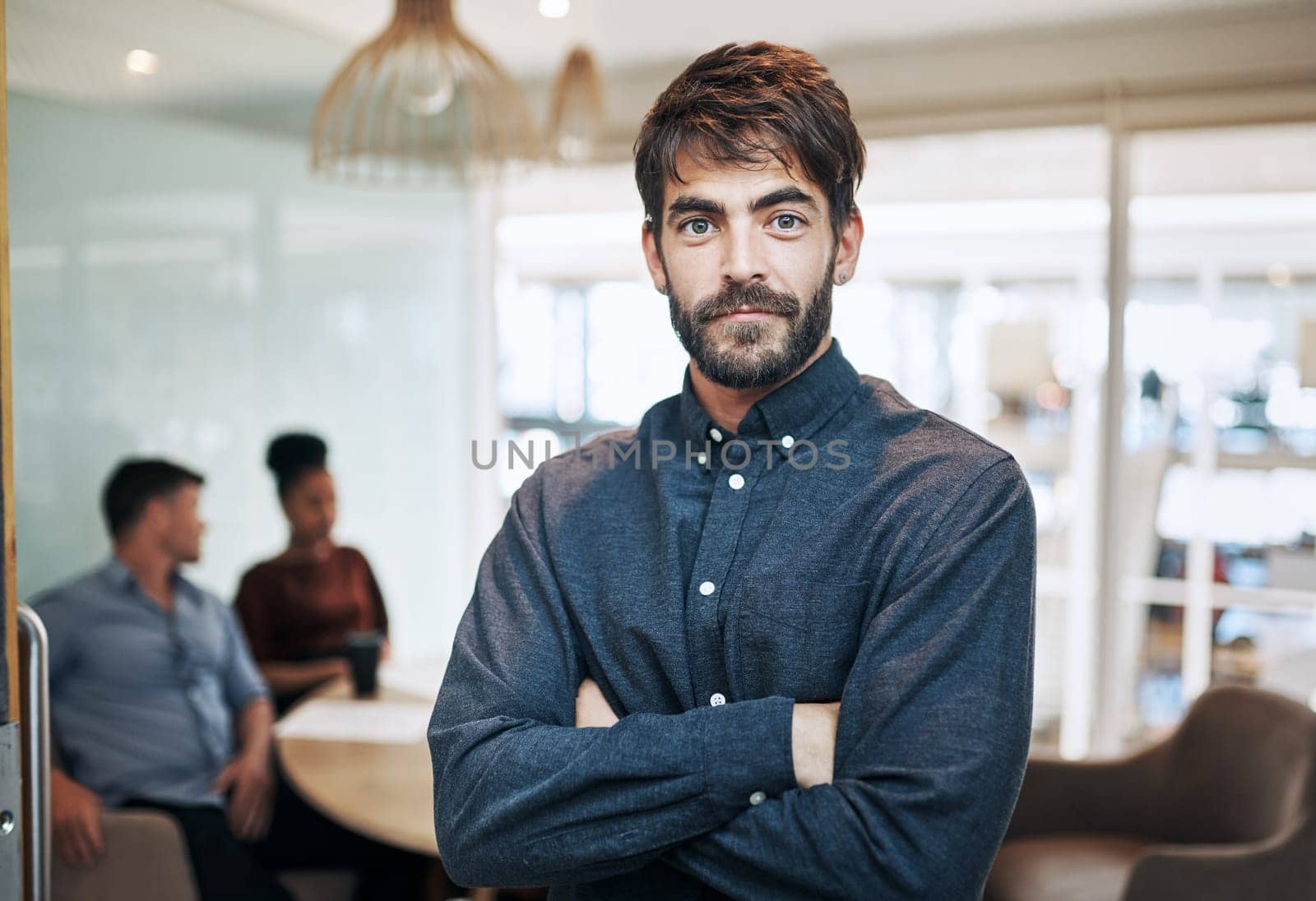 I know my worth and I will prove it. Portrait of a young businessman standing in an office with his colleagues in the background