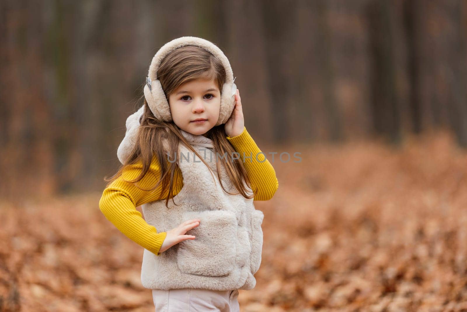 little girl in headphones walks through the autumn forest