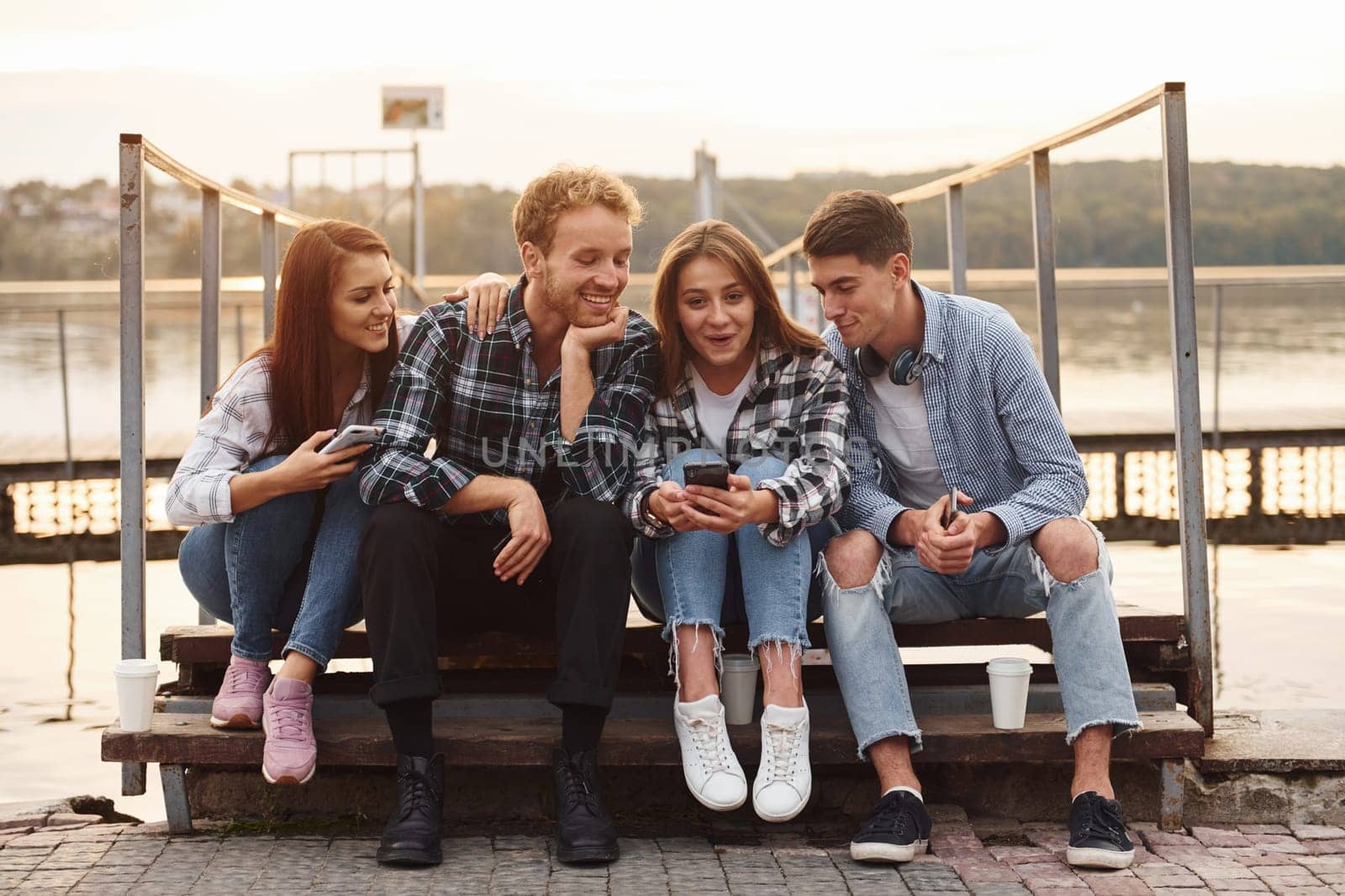 Near the lake. Group of young cheerful friends that is outdoors having fun together.