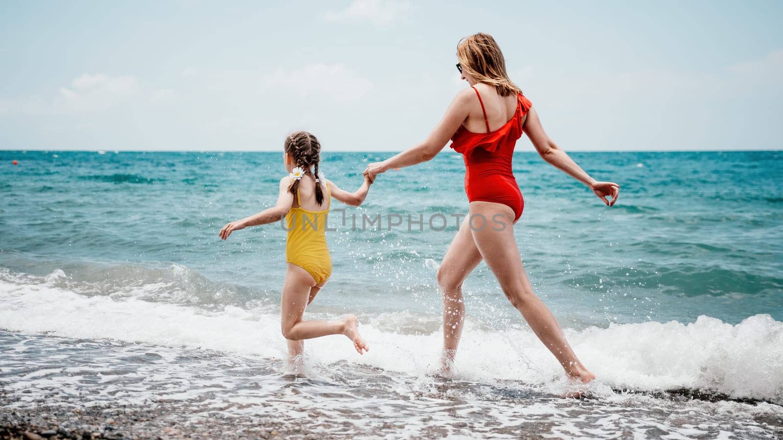 Happy loving family mother and daughter having fun together on the beach. Mum playing with her kid in holiday vacation next to the ocean - Family lifestyle and love concept.