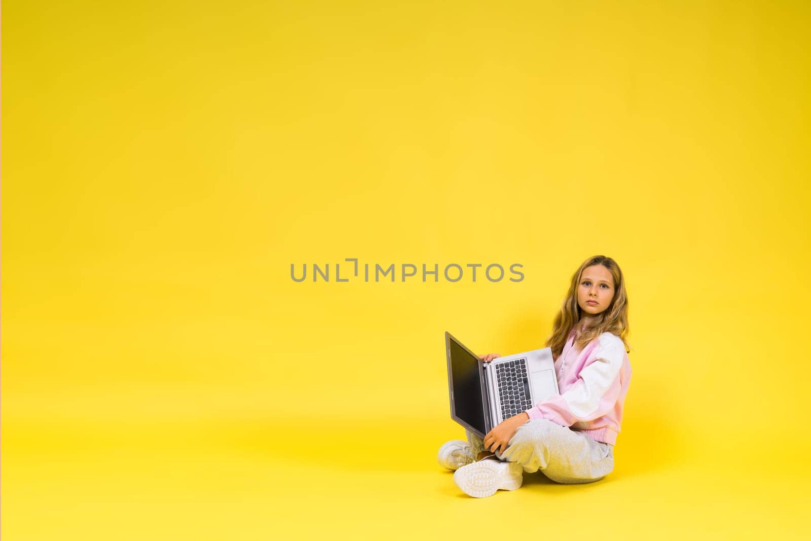 Positive kid sit with a laptop read homework wear casual style cloth isolated over yellow background