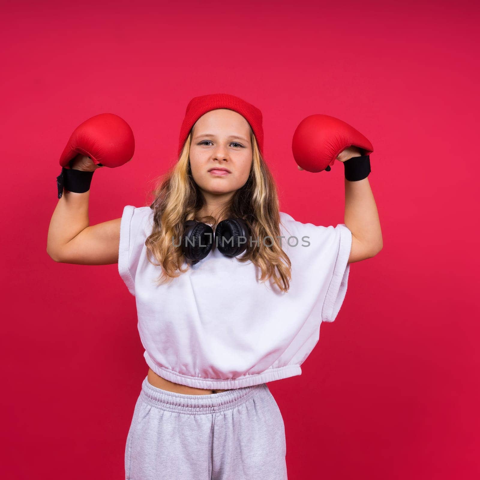 Cute little girl in boxing gloves on red background studio by Zelenin