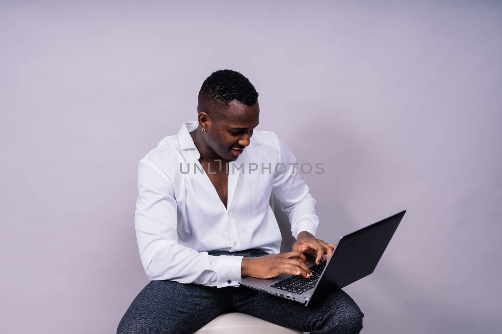 Optimistic african-american male student in casual shirt using laptop pc isolated by Zelenin