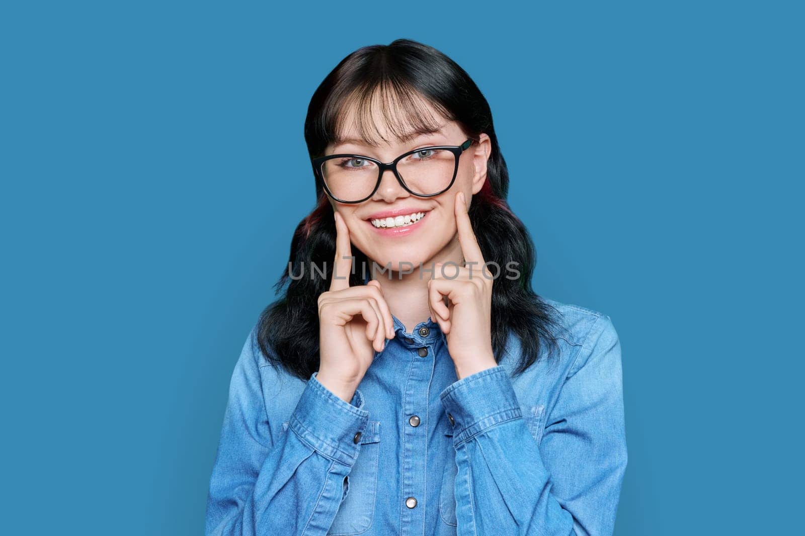 Young woman showing smile with teeth, on white background by VH-studio