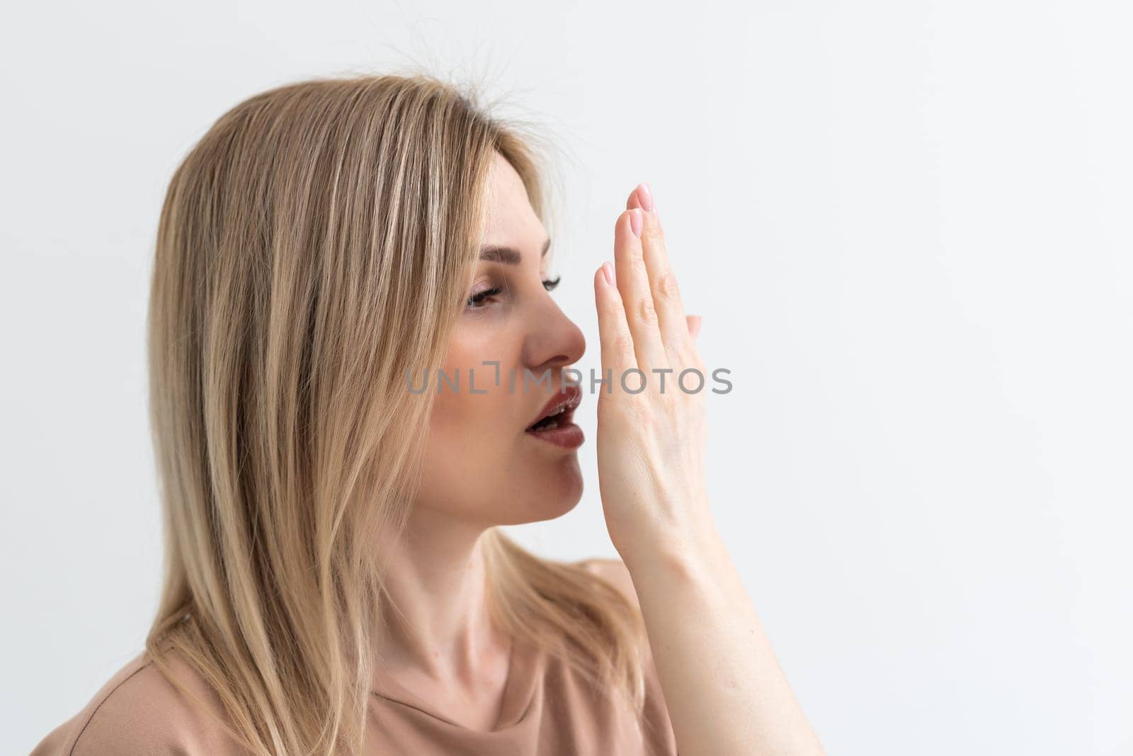 young woman checking her breath with her hand.