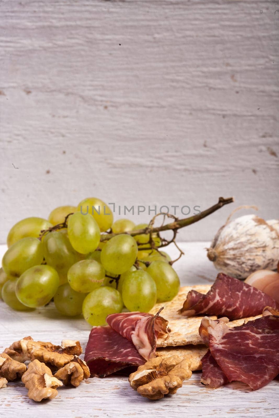 Grape, crackers and ham on white wooden background by DCStudio