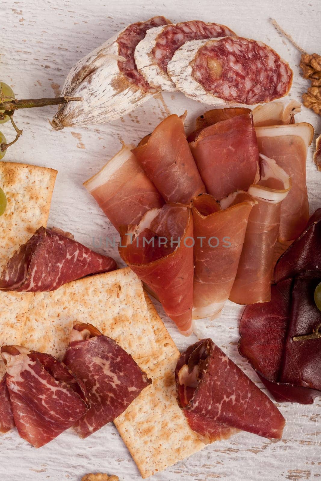 Ham, nuts, crackers and grape on white wooden background by DCStudio