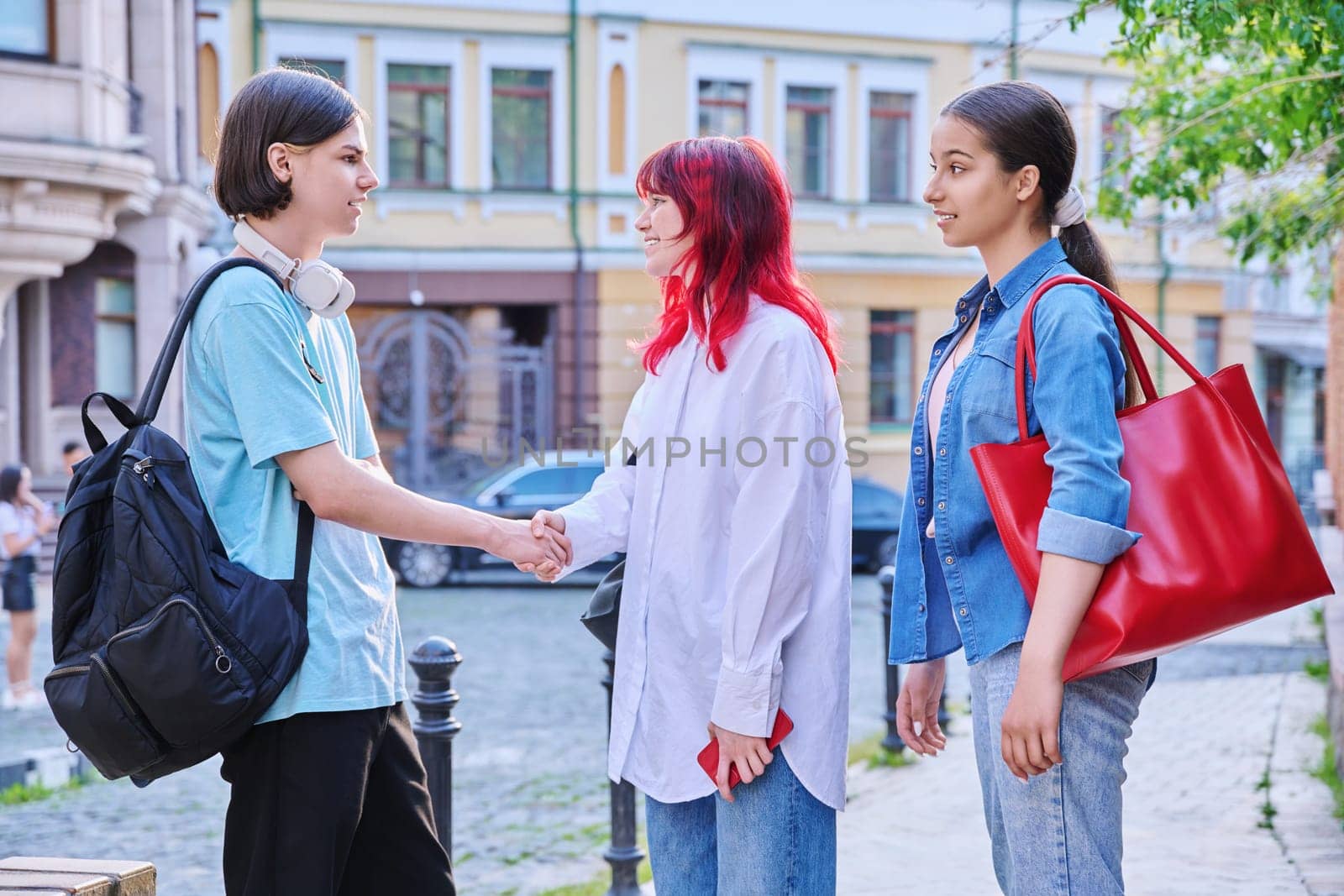 Meeting teenage friends outdoor, on street of city. Happy laughing talking young females and guy. Youth, communication, friendship, emotions, high school, college concept
