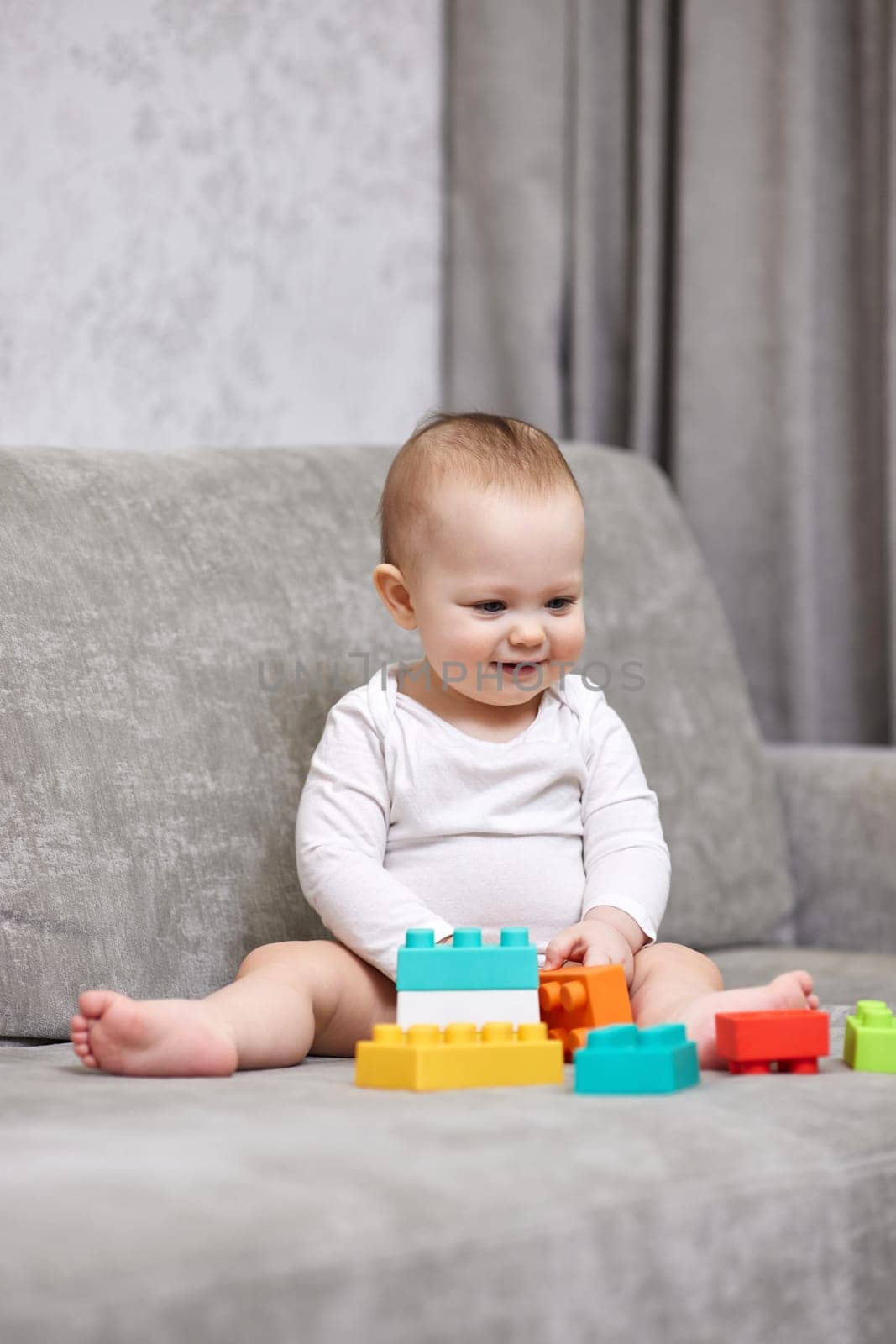 cute baby girl playing with colorful toy blocks at home