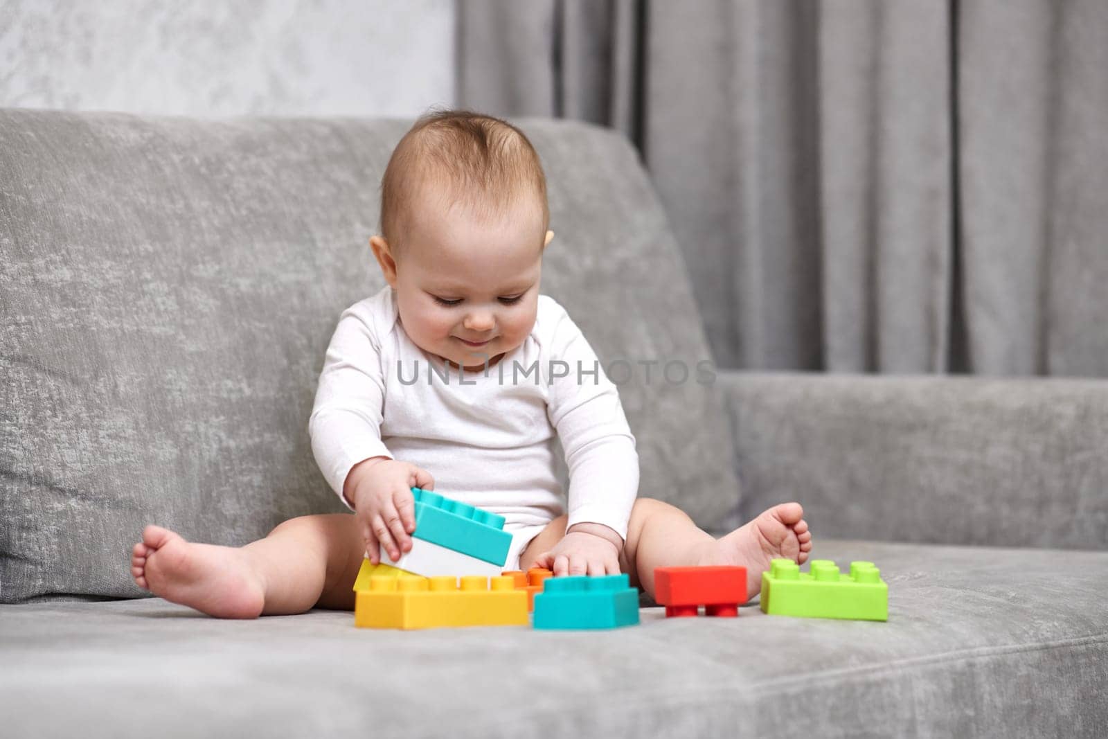 cute child girl playing with colorful toy blocks at home