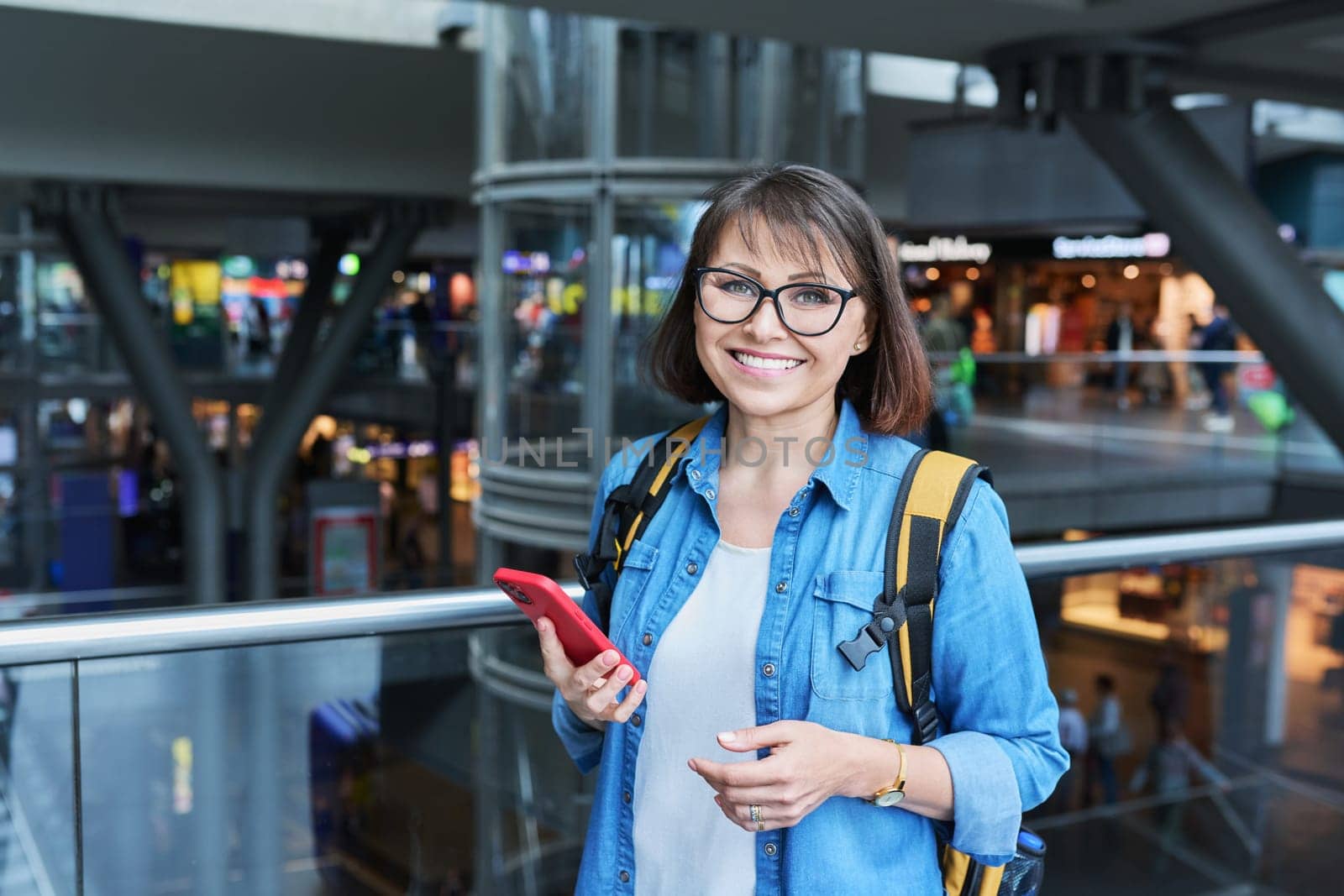 Woman on in modern building of city transport station with smartphone. Female using fast internet connection network for online ticketing service mobile application timetable transport route