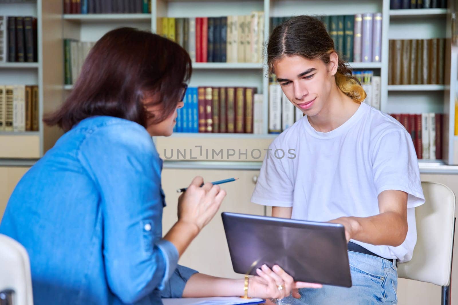 Woman school psychologist talking and helping student, teenage guy. Female teacher, mentor working with teenager. Mental health of adolescents, psychology, social issues, professional help of counselor