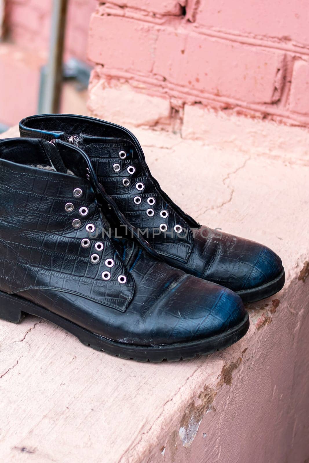 Old black discarded boots in a landfill close up
