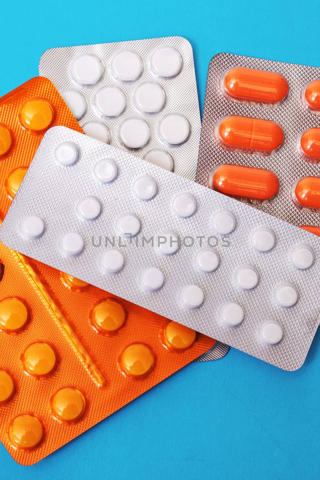 Pile of packs of pills on blue background close up