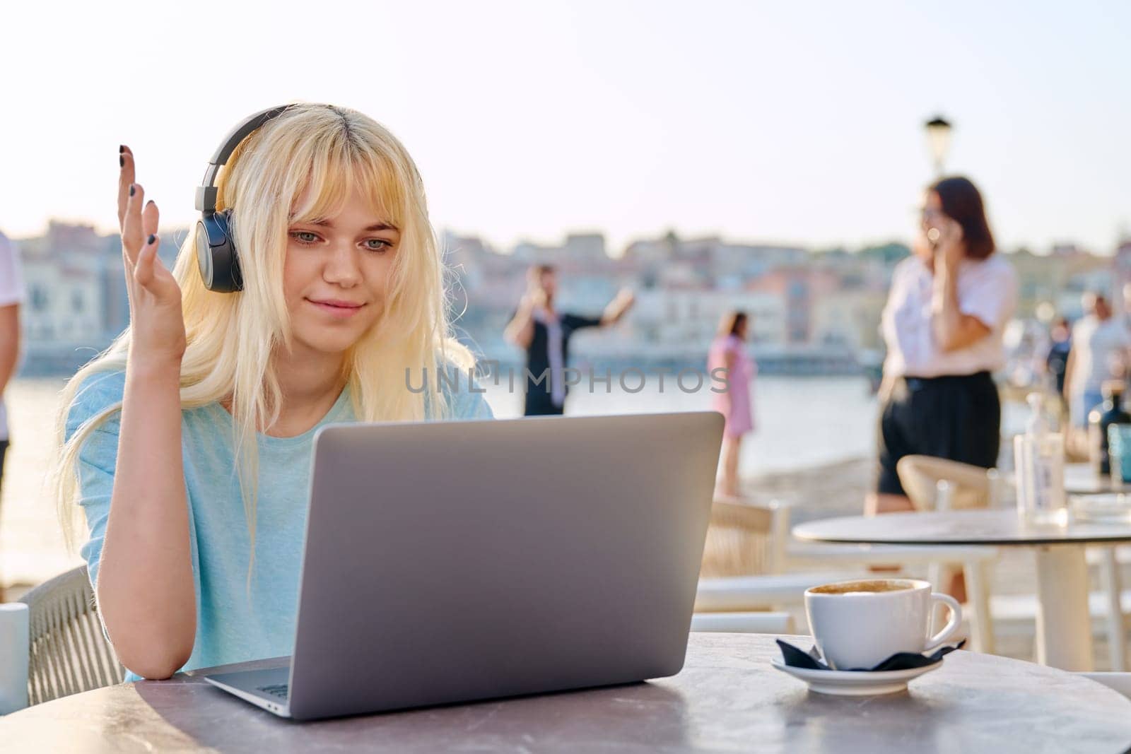 Smiling beautiful teenage girl in headphones looking into laptop by VH-studio