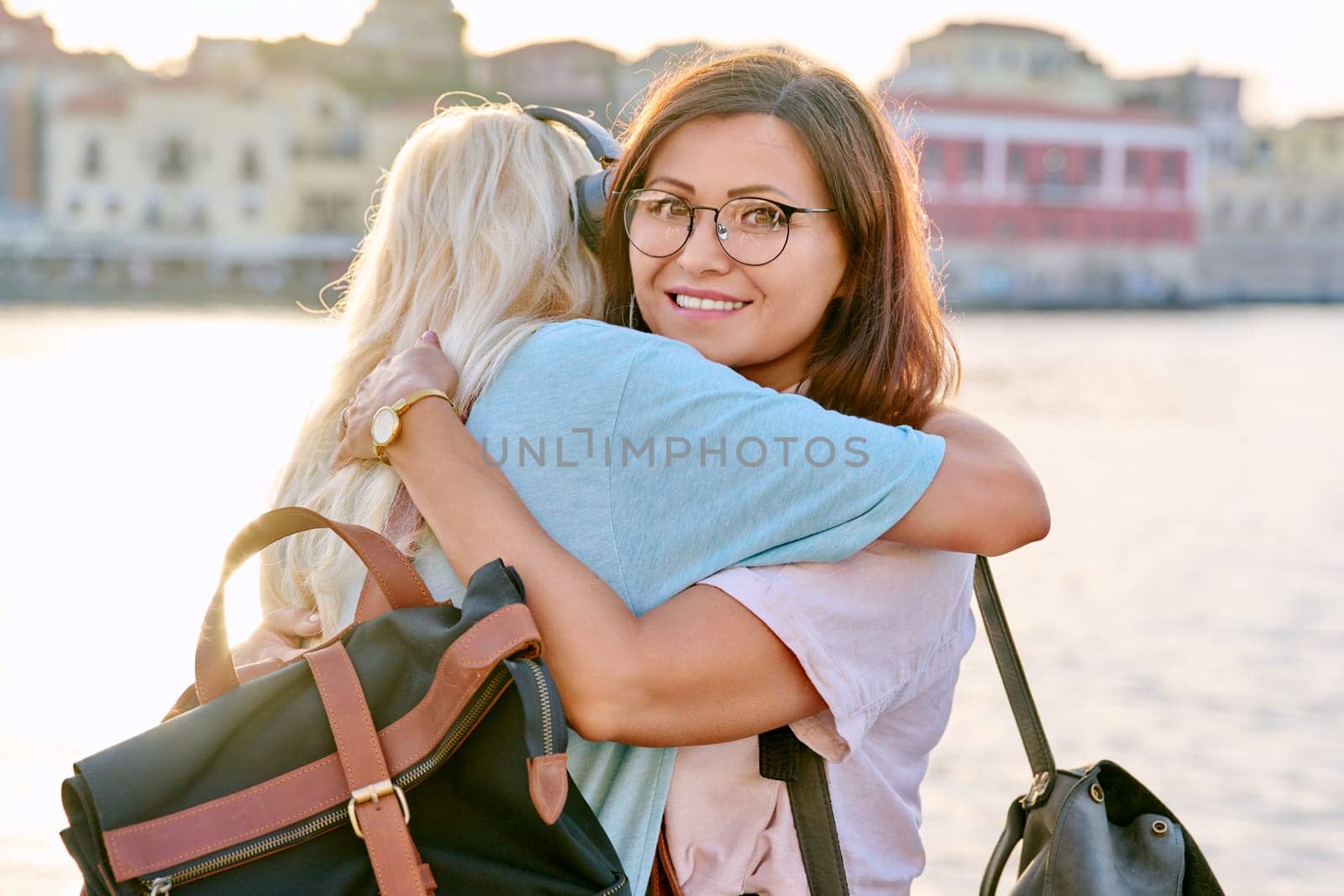Portrait of mother and teenage daughter hugging happy. Family, girl and mom together on city's seaside summer embankment at sunset. Family, motherhood, mother's day, happiness, relationship, love