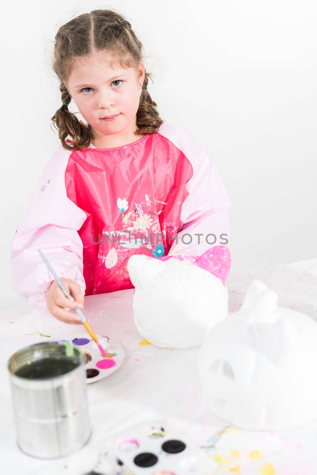 Little girl painting Halloween pumpkin with acrylic paint.