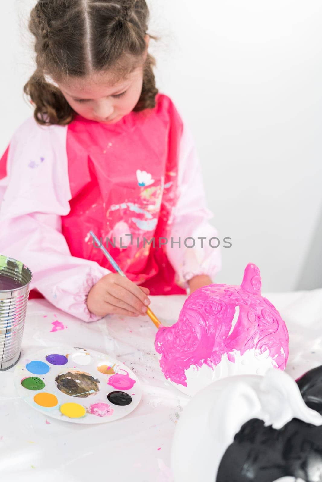 Little girl painting Halloween pumpkin with acrylic paint.