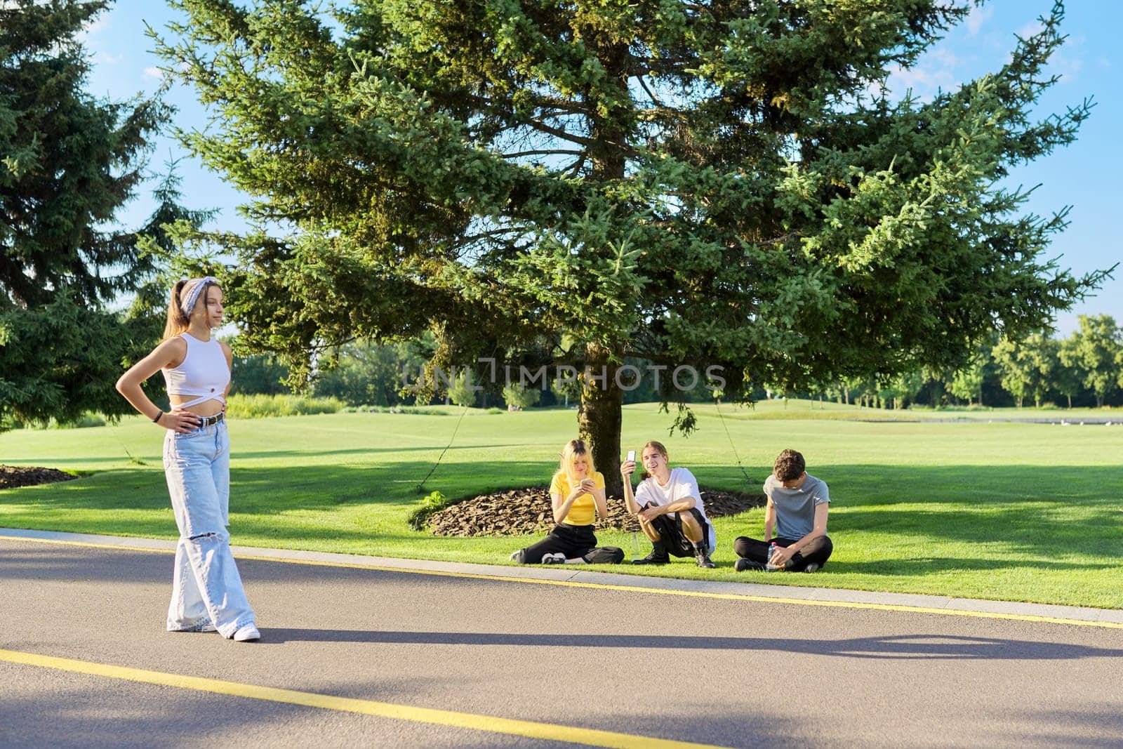 Group of hipsters teenagers having fun in park on road, teenage girl dancing street dance, friends filming video on smartphone. Vacation, leisure, friendship, lifestyle, teenagers concept