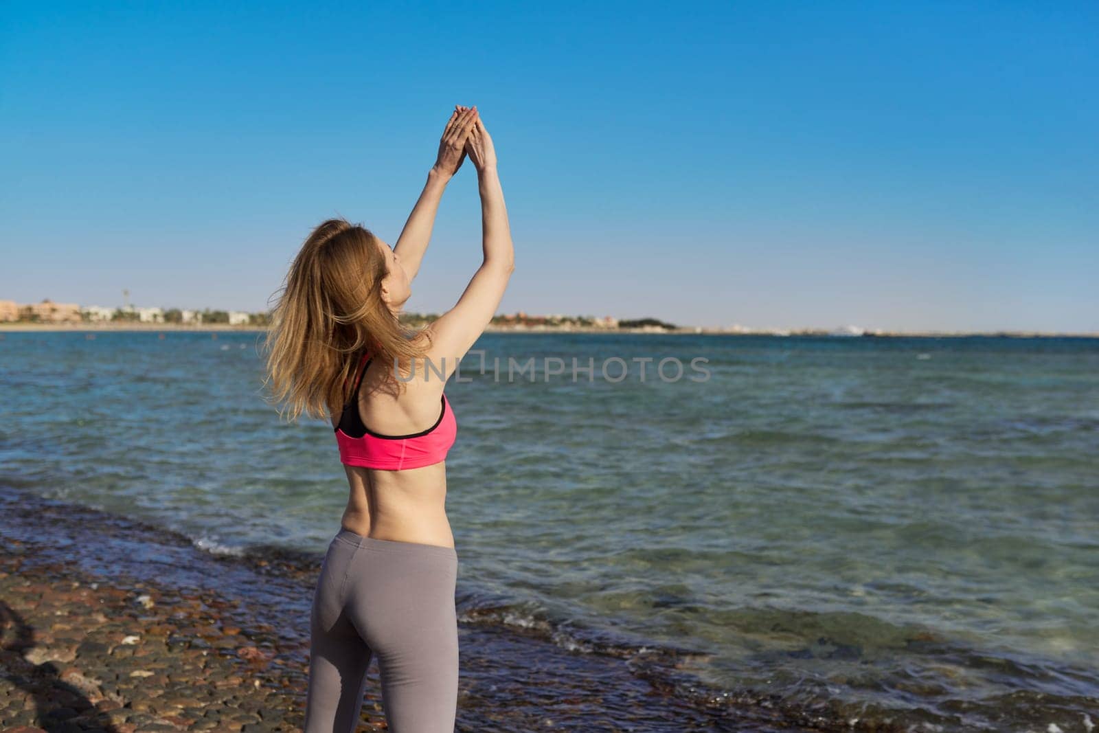 Active middle aged woman in sportswear doing workout on the beach. by VH-studio