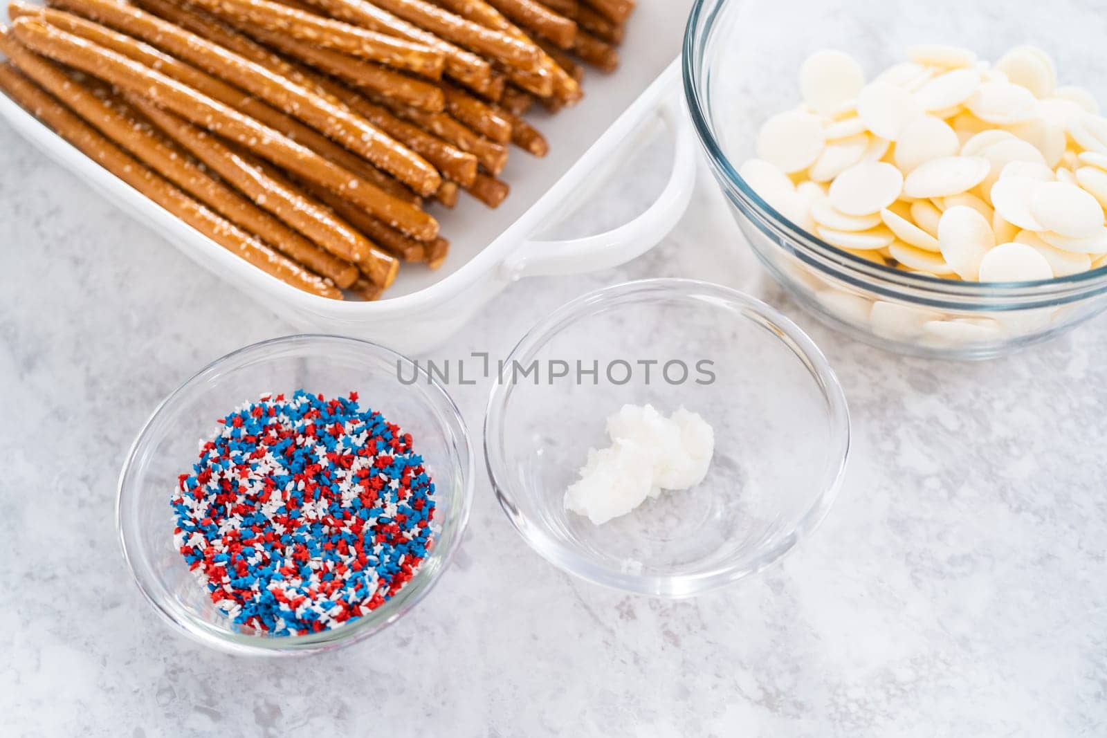 Ingredients in glass mixing bowls to prepare chocolate dipped pretzel rods for the July 4th celebration.
