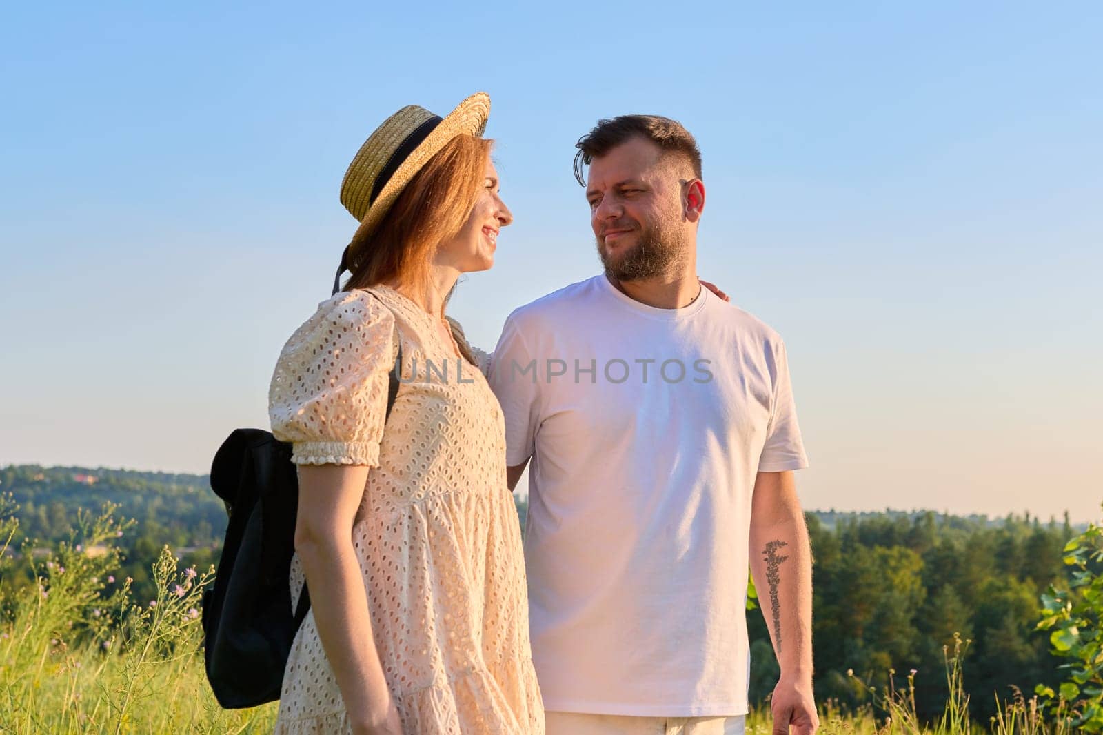 Portrait of happy adult couple on summer sunny day. Beautiful people man and woman embracing in nature, looking at each other. Family, happiness, holidays, relationships, middle aged people