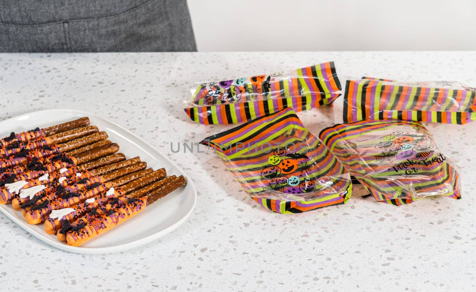 Packaging Halloween chocolate-covered pretzel rods with sprinkles into gift bags.