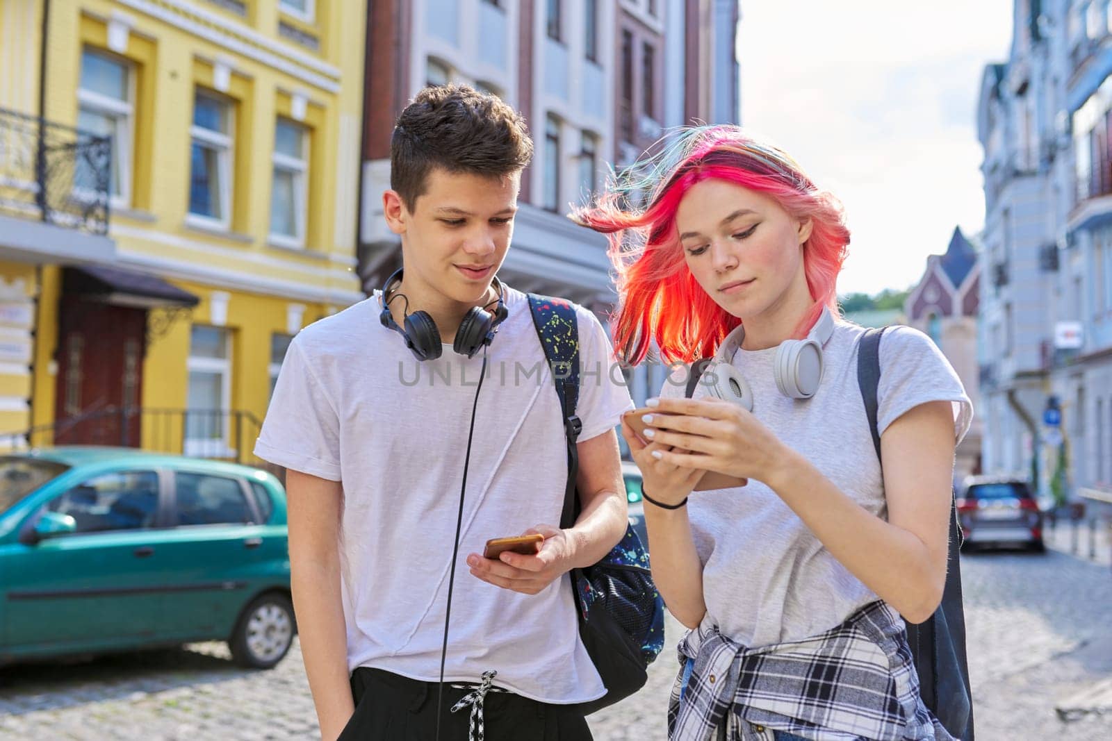 Couple of trending teenagers friends with smartphone on city street by VH-studio