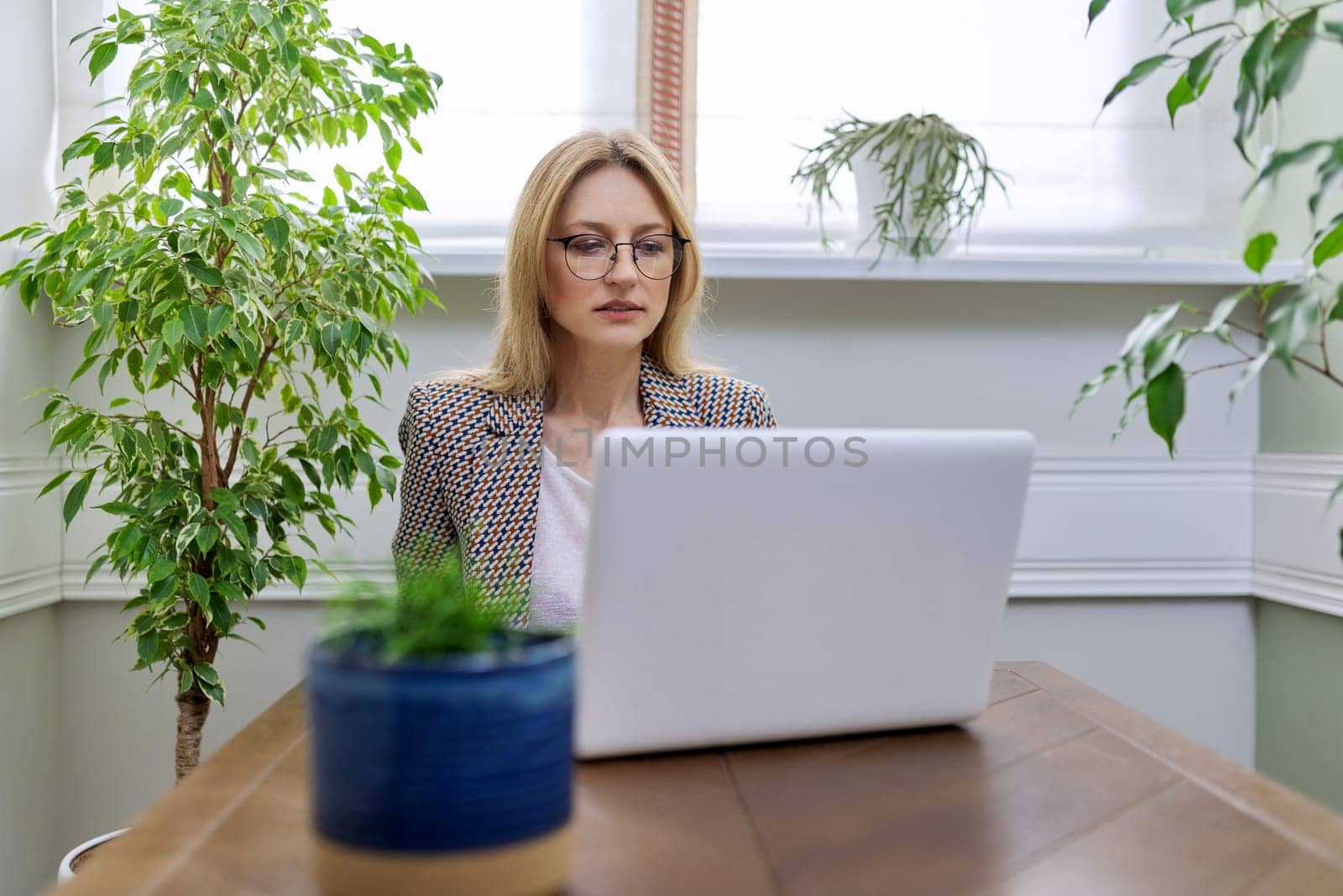 Middle aged business woman working at home using laptop, by VH-studio