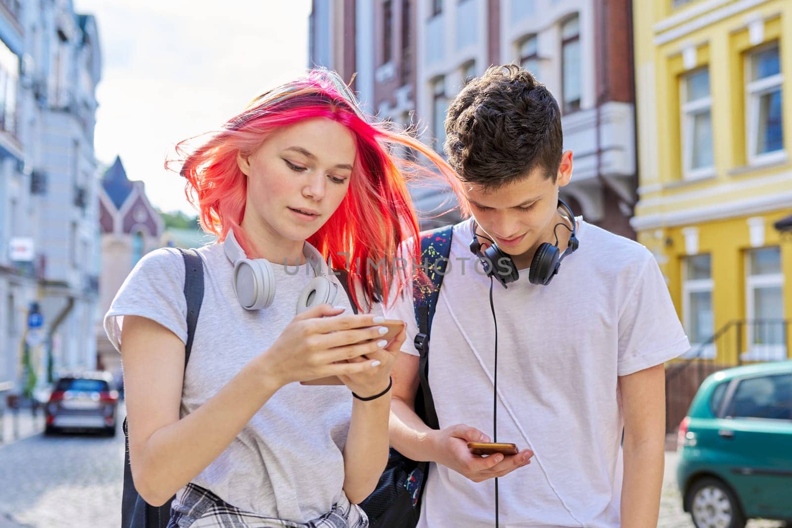 Fashionable modern youth, lifestyle, technology, urban style. Couple of trending teenagers friends with smartphone on city street