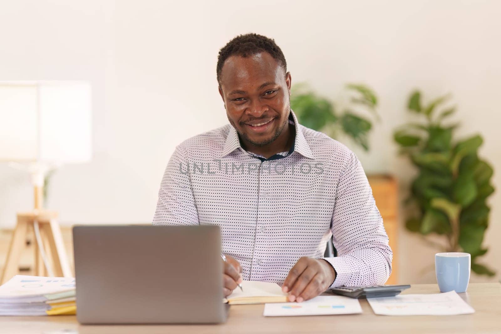 Smiling American African makes financial report and studies annual figures, analyzes profits. Accountant checks status of financial by itchaznong