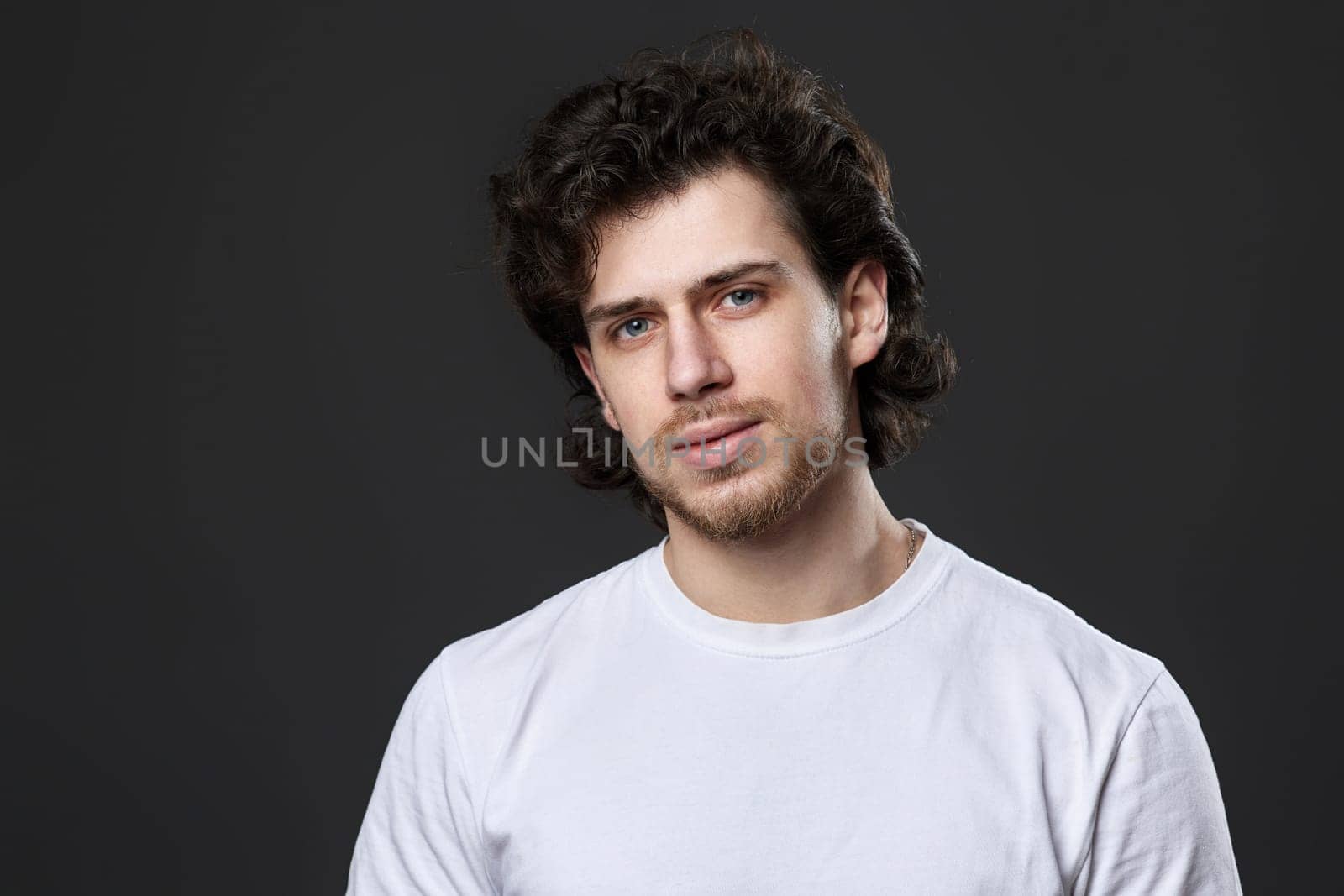 portrait of calm young bearded man on dark gray background