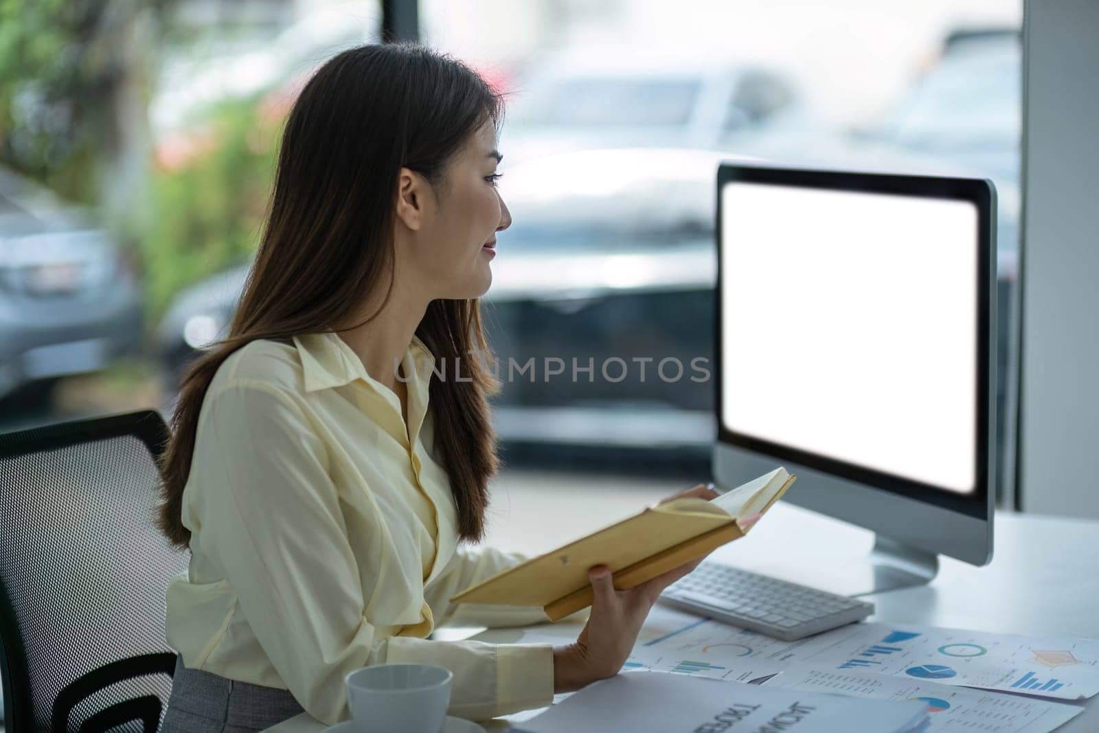 woman hand using laptop with mock up white screen and taking notes. work from home concept