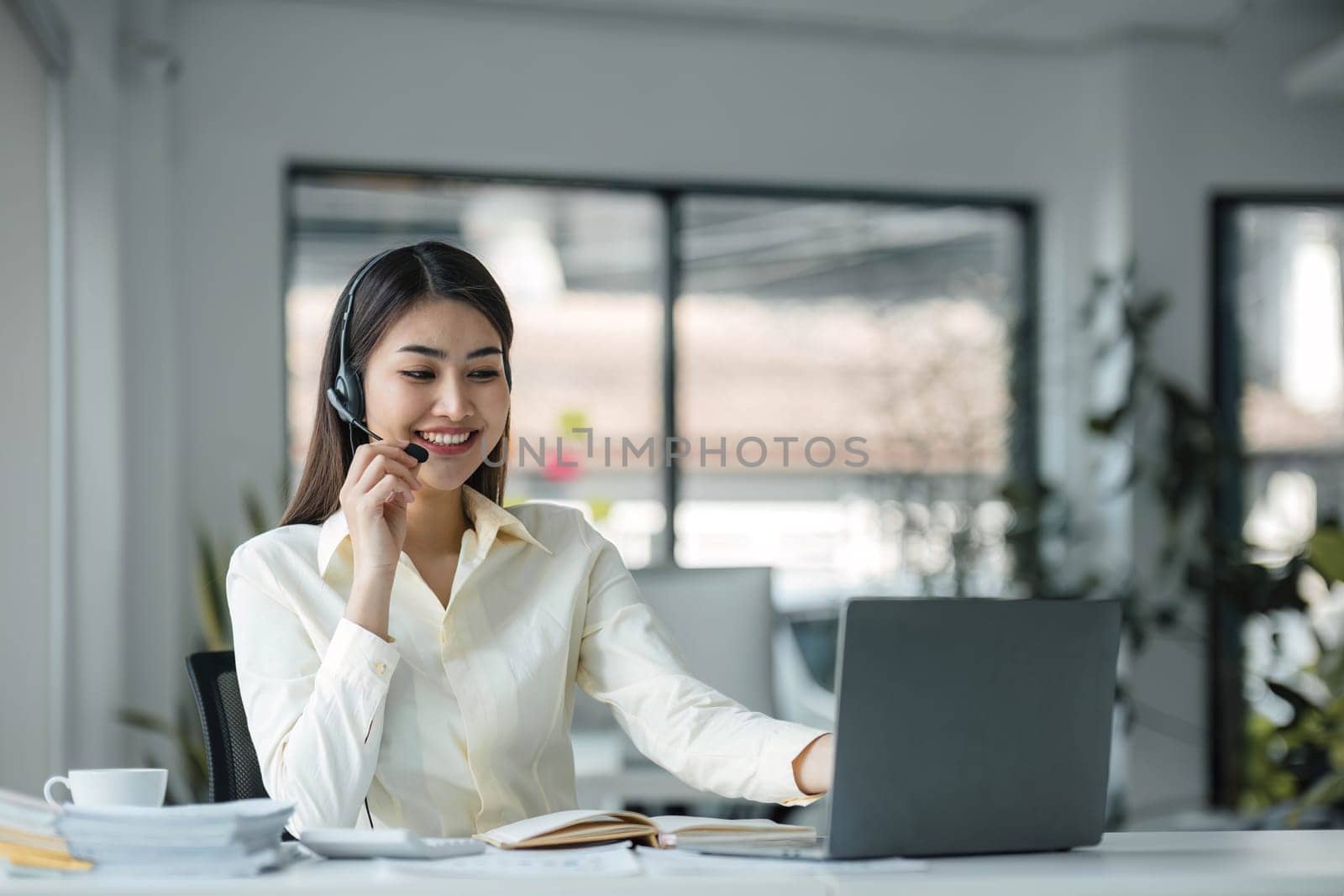 close up call center operator in wireless headset talking with customer, woman in headphones with microphone consulting client on phone in customer support service, looking at computer screen