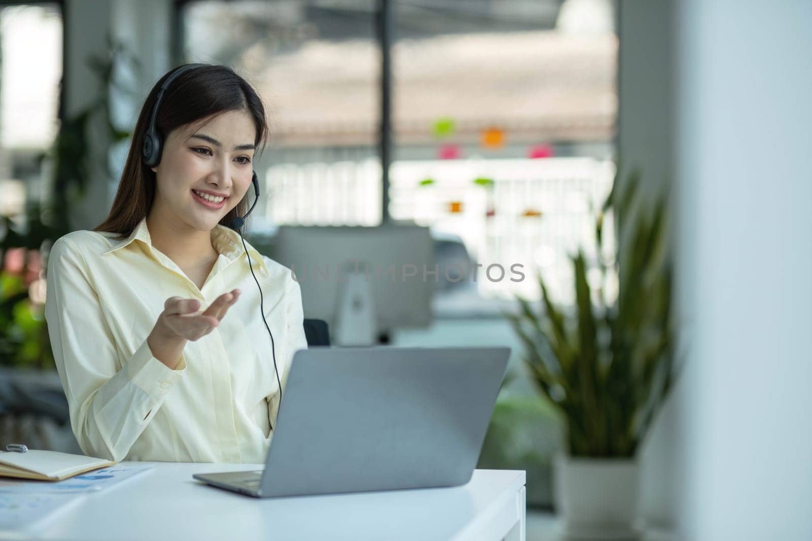 close up call center operator in wireless headset talking with customer, woman in headphones with microphone consulting client on phone in customer support service, looking at computer screen