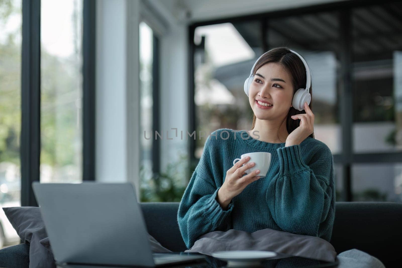 Work at home young asian woman working on laptop computer while sitting and hold coffee cup at home Morning lifestyle concept..