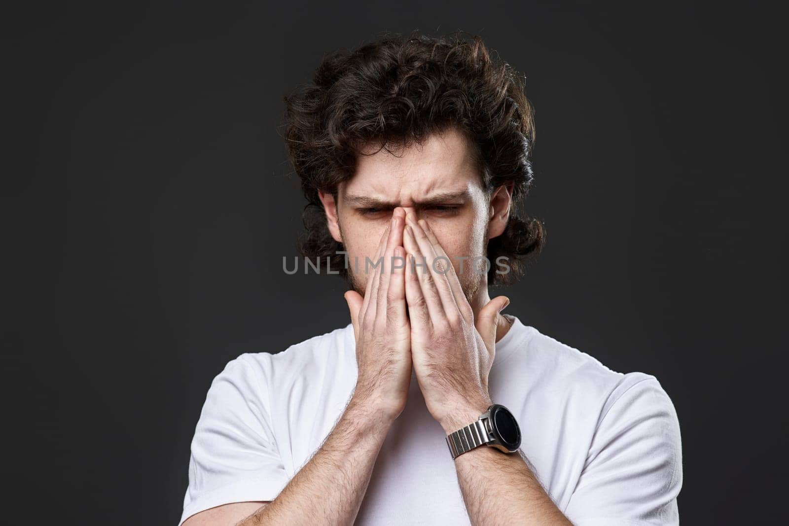 Portrait of frustrated young man on dark gray background. sadness