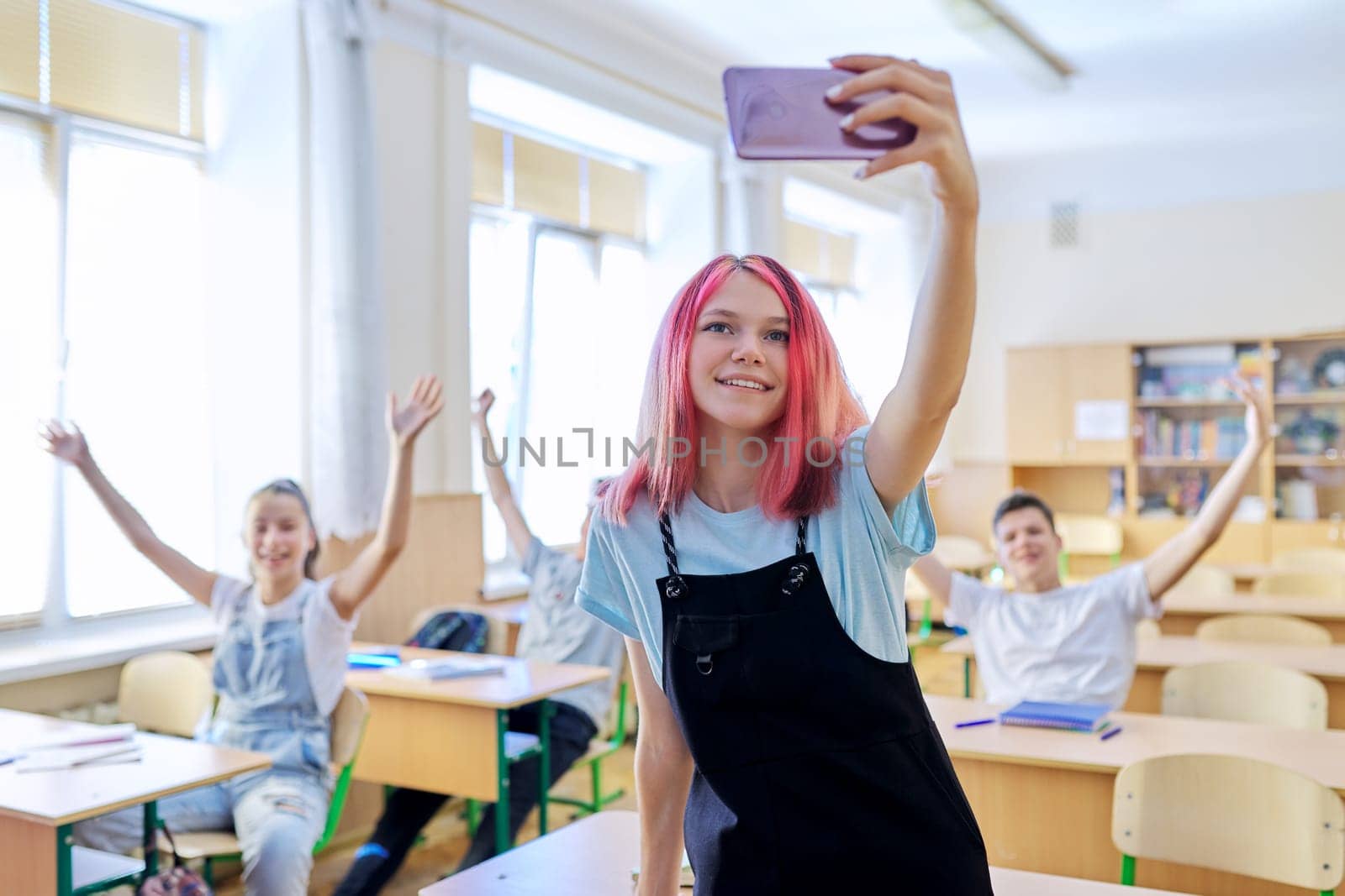 Teenagers students having fun in the classroom, bright trendy girl taking selfie photo with group of classmates friends at school